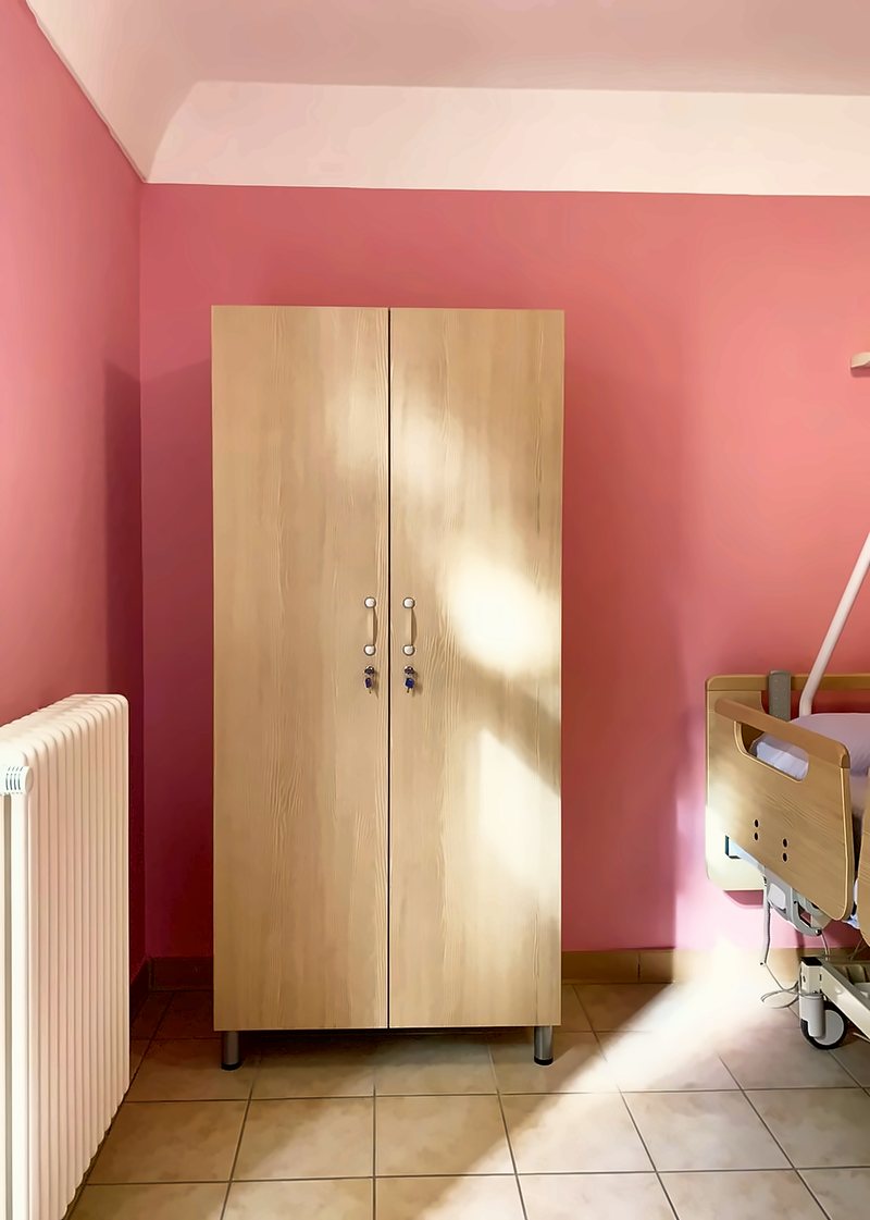 Armadio in legno chiaro in una camera dalle pareti rosa