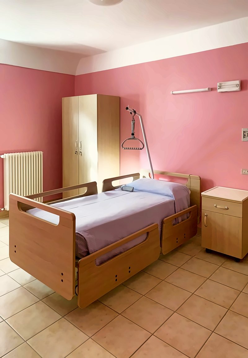 Camera con letto articolato, asta alzamalati con triangolo, armadio e comodino