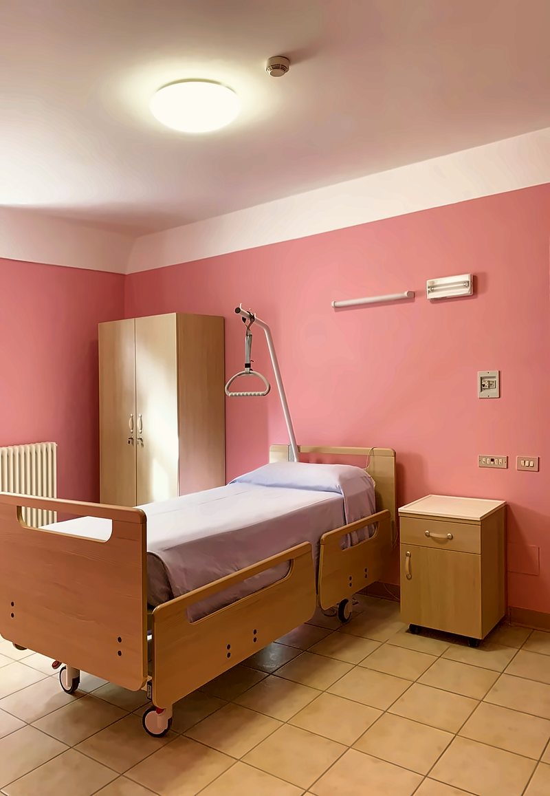 Camera con letto articolato, armadio, comodino e pareti rosa