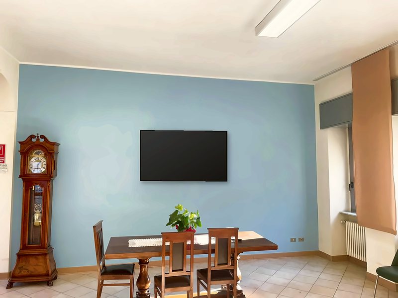 Salotto con pareti azzurre, orologio a pendolo e tavolo con sedie